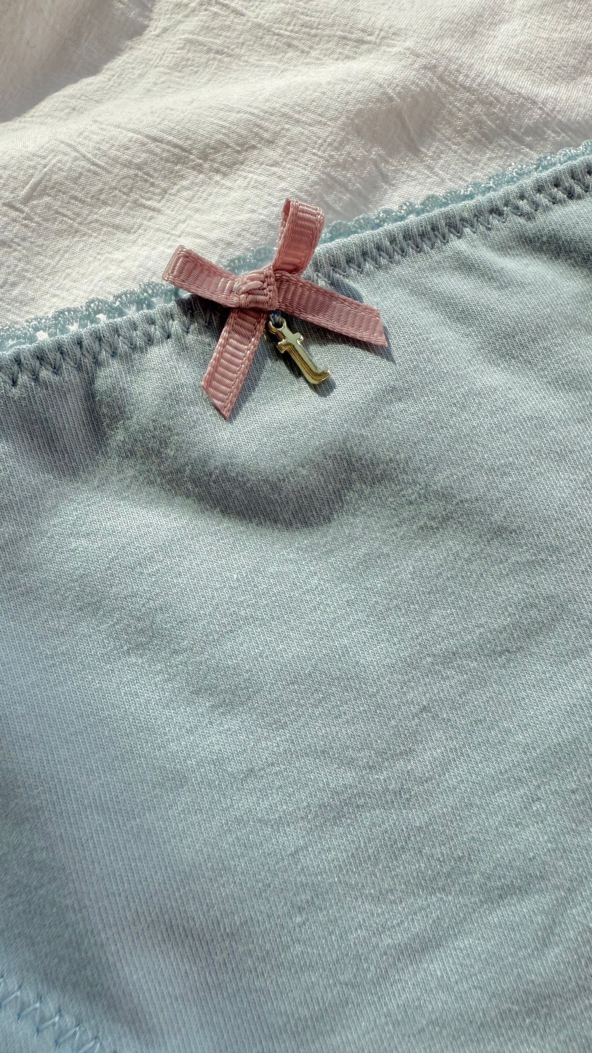 Close-up detail of Teysha organic cotton picot edge bikini brief in dusty blue — delicate scalloped trim and pink bow, GOTS-certified for tween girls